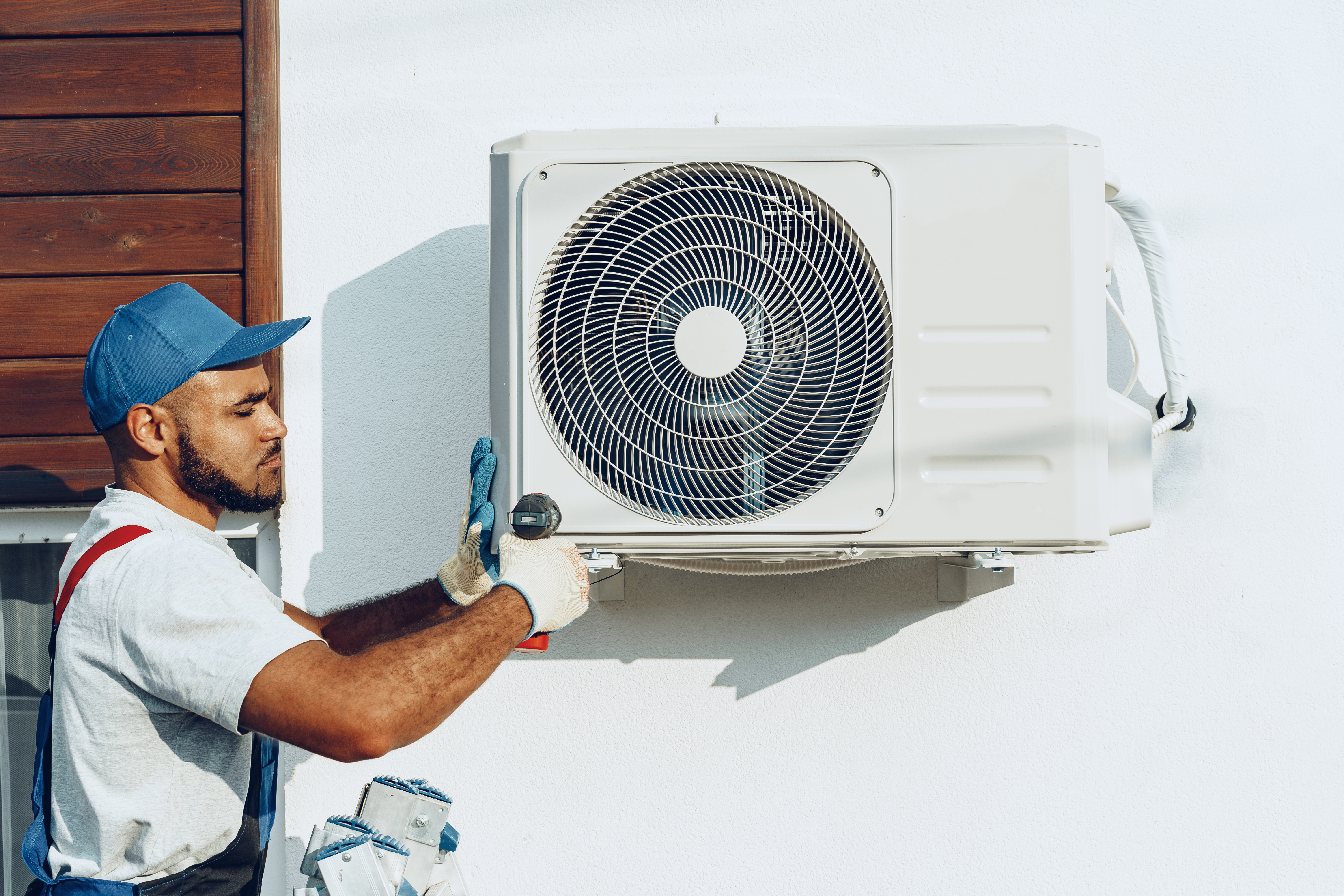 Repairman in uniform installing the outside unit of air conditioner close up